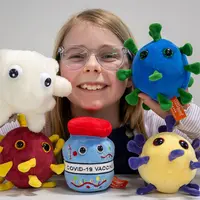 A girl proudly presents four stuffed animals, all featuring the word